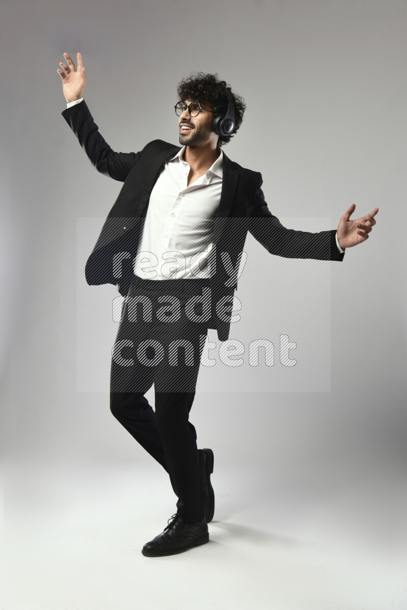 A man wearing formal standing and putting on headphones on white background