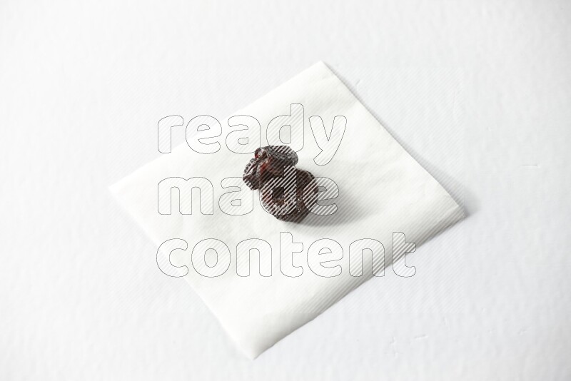 Two dried plums on a piece of paper on a white background in different angles
