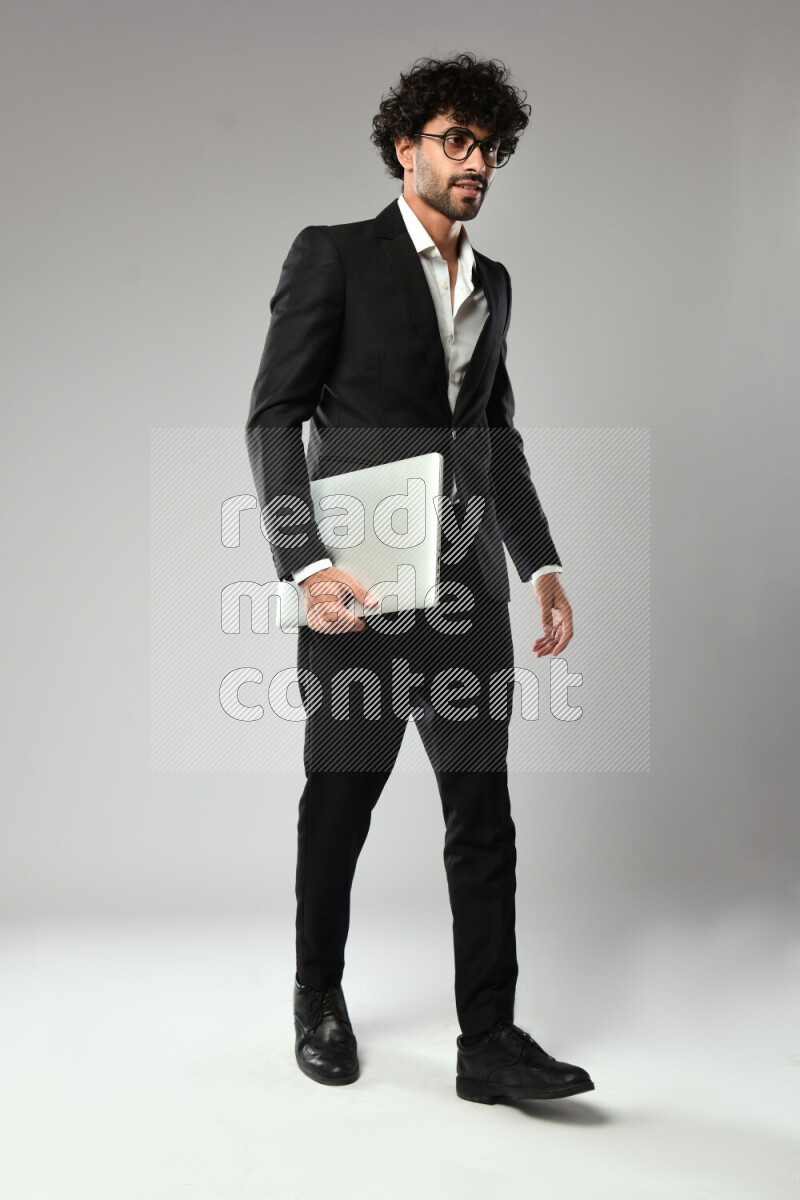 A man wearing formal standing and holding a laptop on white background