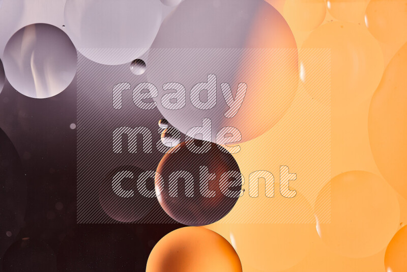 Close-ups of abstract oil bubbles on water surface in shades of black and orange