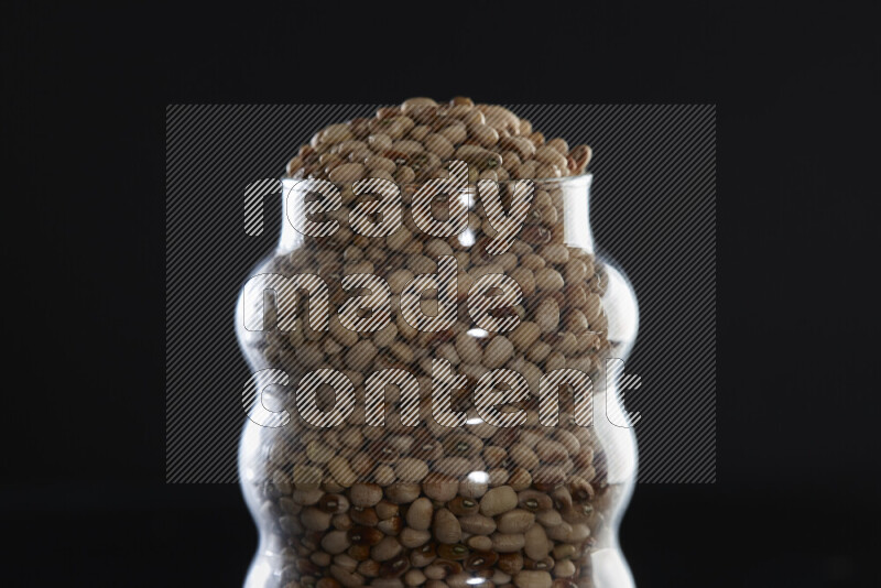 Black-eyed peas in a glass jar on black background