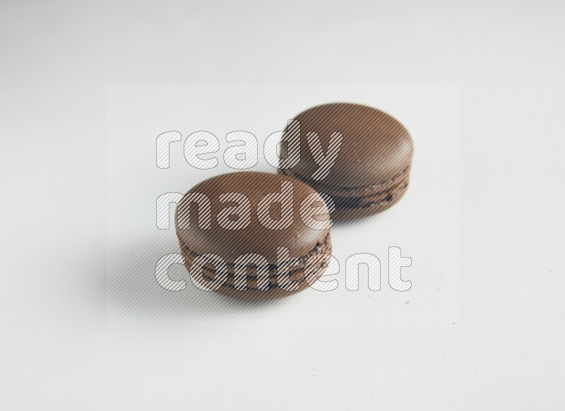 45º Shot of two Brown Dark Chocolate macarons on white background