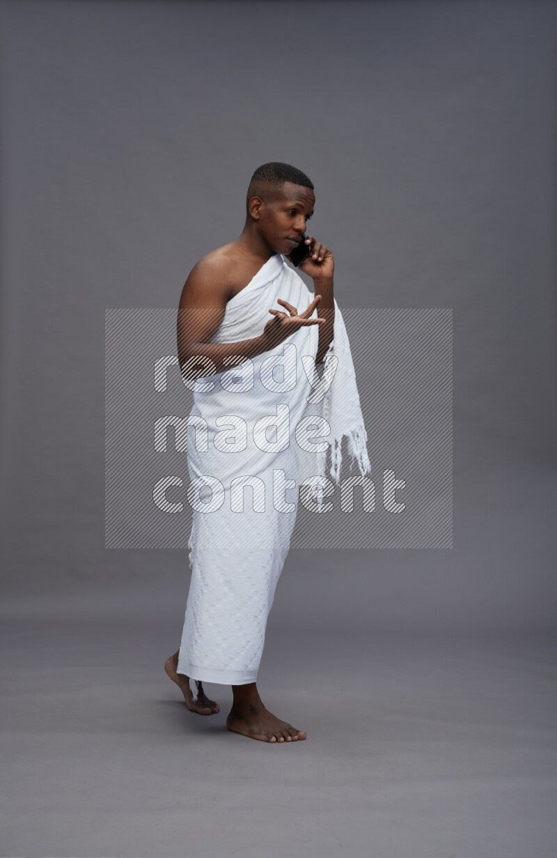 A man wearing Ehram Standing talking on phone on gray background