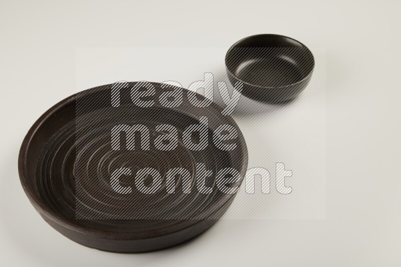black pottery plate and black bowls on white background