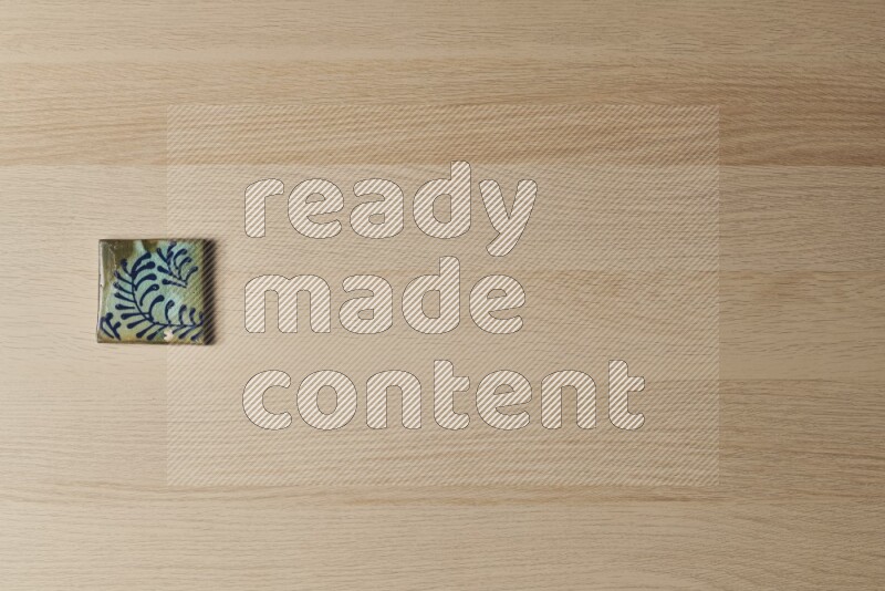 A decorative pottery coaster on light wooden background