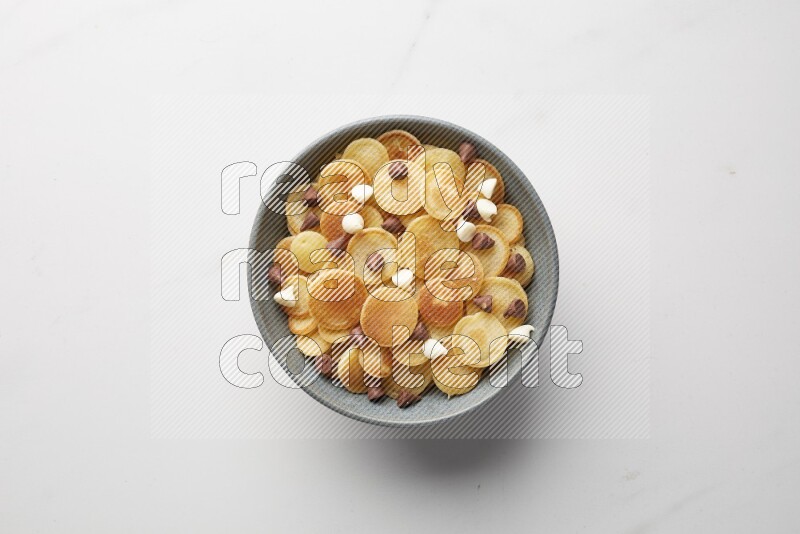 Top-view shot of mixed chocolate chips cereal pancakes in a round bowl on white background