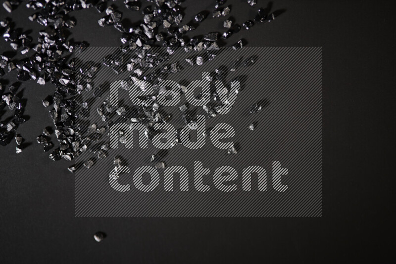 قطع زجاجية سوداء لامعة متناثرة على خلفية سوداء