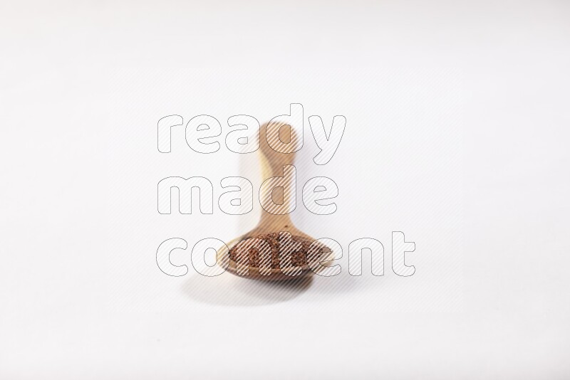 A wooden ladle full of garden cress seeds on a white flooring