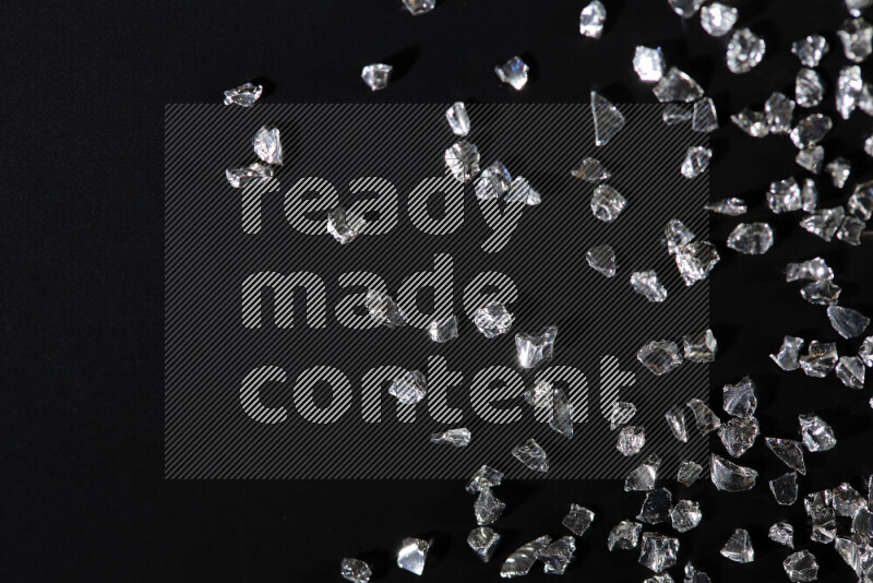 Silver shimmering fragments of glass scattered on a black background