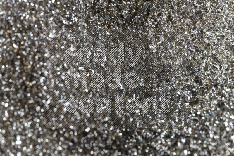 Silver shimmering fragments of glass scattered on a black background