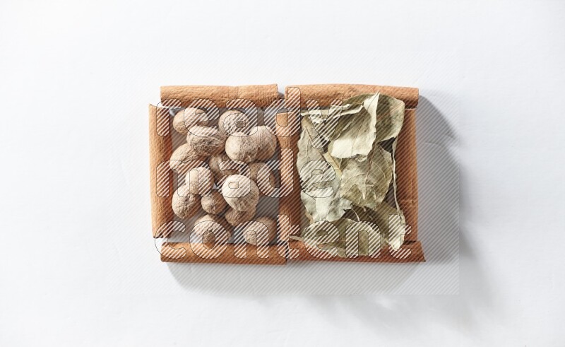 2 squares of cinnamon sticks full of bay laurel leaves and nutmegs on white flooring
