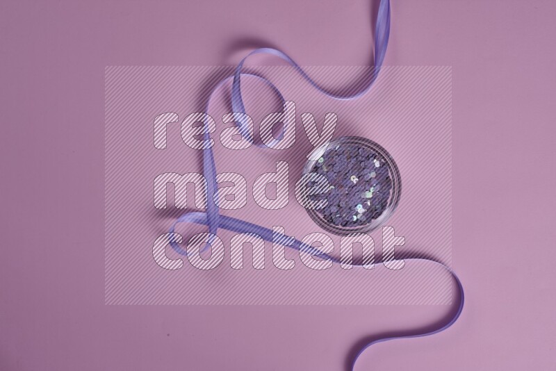 A purple and pink collection of sewing and tailoring tools arranged on a pink background