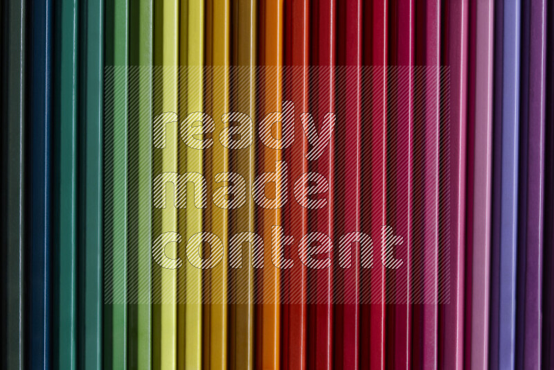 مجموعة من أقلام الرصاص الملونة مرتبة لتعرض تدرجا من الألوان المختلفة علي خلفية رمادية