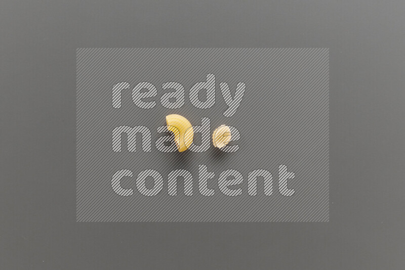 Elbow pasta with other types of pasta on grey background