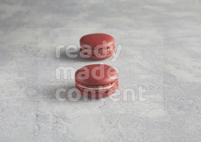 45º Shot of two Red Velvet macarons  on white  marble background