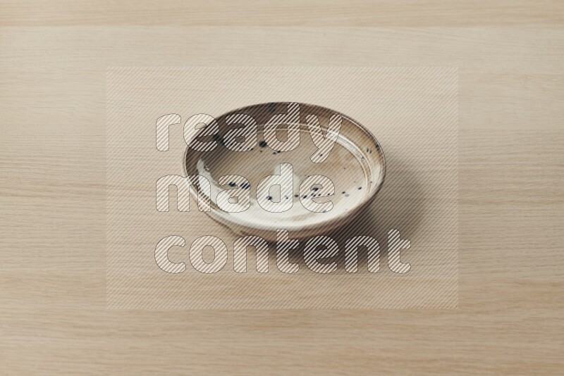 A multicolored pottery plate on light wooden background