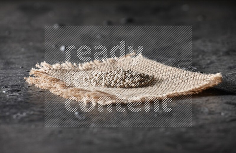 White pepper beads on a burlap piece of fabric on textured black flooring