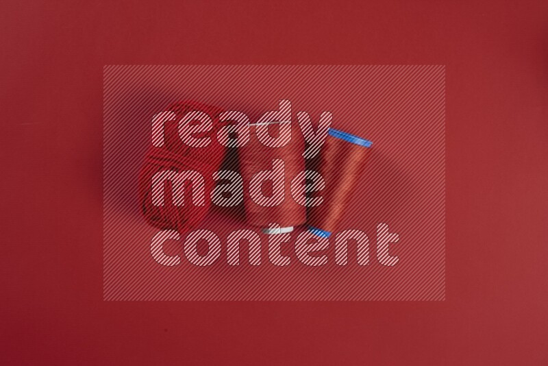 A red collection of sewing and tailoring tools arranged on a red background