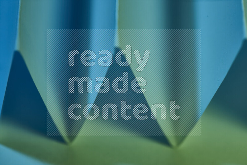 صورة مجردة مقربة تظهر طيات ورقية هندسية حادة بتدرجات اللون الأخضر والأزرق