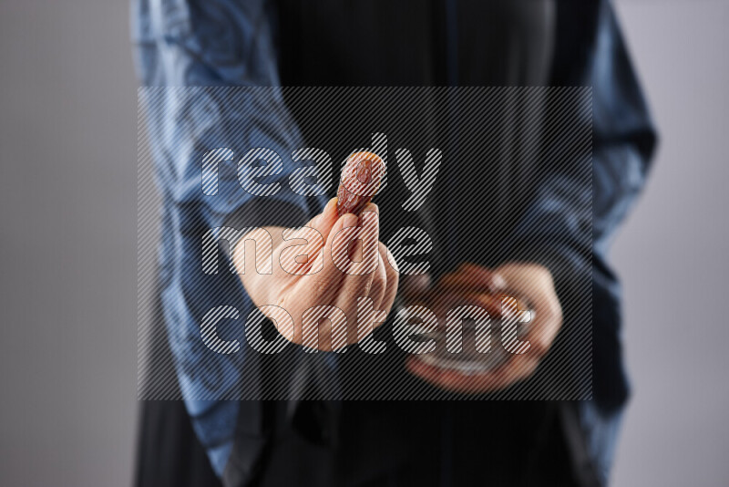 امرأة ترتدي عباءة تحمل أنواع مختلفة من التمر في أوضاع متعددة