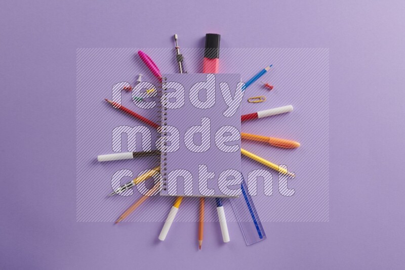 دفتر ملاحظات باللون الأرجواني مع مستلزمات مدرسية مختلفة على خلفية أرجوانية