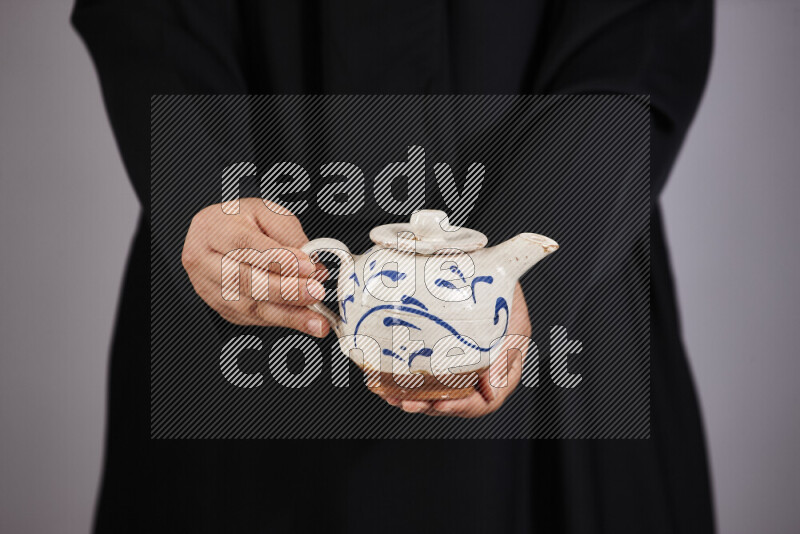 A woman in black abaya holding different pottery essentials in different positions