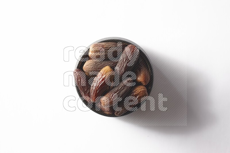 Dates in a black pottery bowl on white background