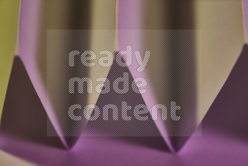 A close-up abstract image showing sharp geometric paper folds in pink gradients and warm tones