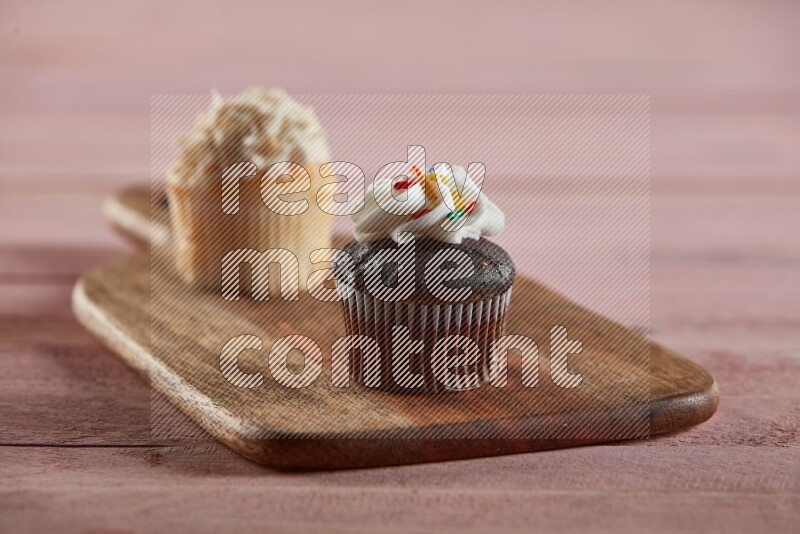 Chocolate mini cupcake topped with cream on a wooden board