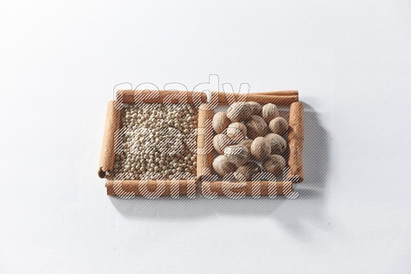 2 squares of cinnamon sticks full of white pepper and nutmegs on white flooring