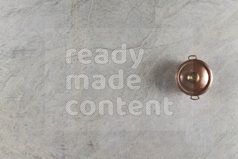 A small copper pot on grey marble background