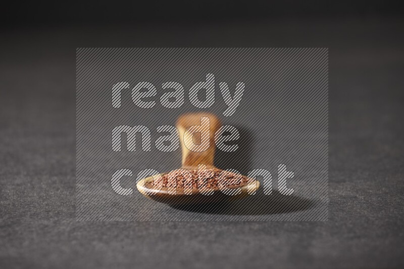 ملعقة خشبية كبيرة ممتلئة ببذور حب الرشاد علي خلفية سوداء