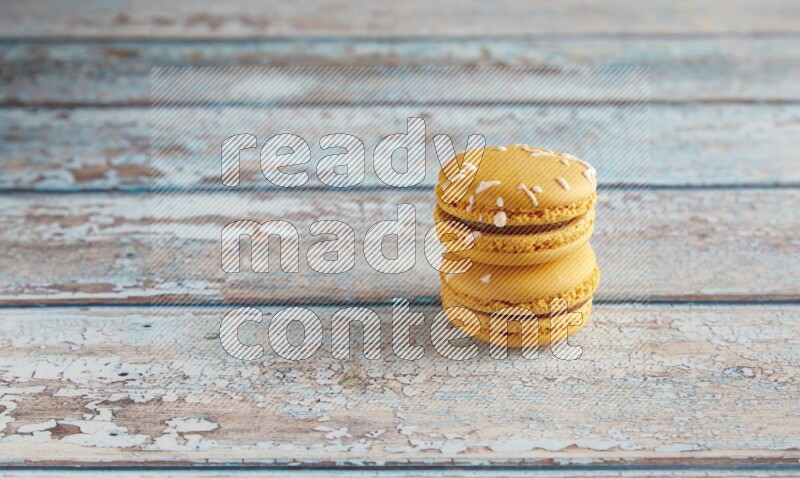 45º Shot of two Yellow Piña Colada macarons on light blue wooden background