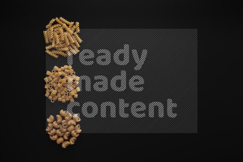 Different pasta types in 3 bunches on black background
