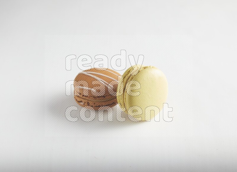 45º Shot of of two assorted Brown Irish Cream, and Yellow Lime macarons on white background