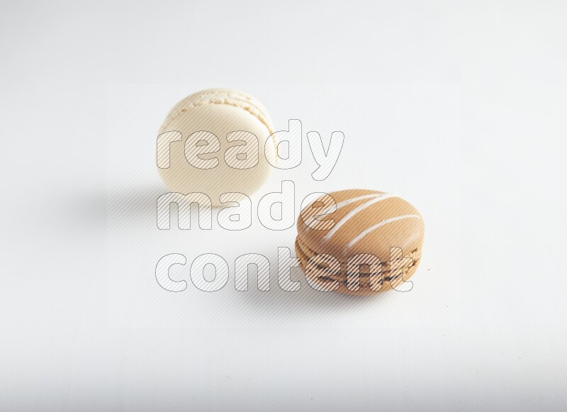 45º Shot of of two assorted Brown Irish Cream, and White Caramel fleur de sel macarons on white background