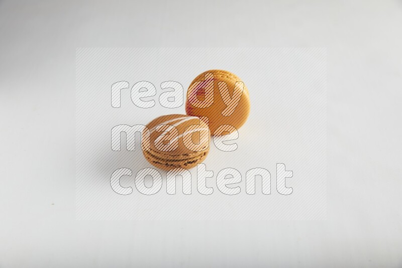 45º Shot of of two assorted Brown Irish Cream, and Orange Exotic macarons on white background