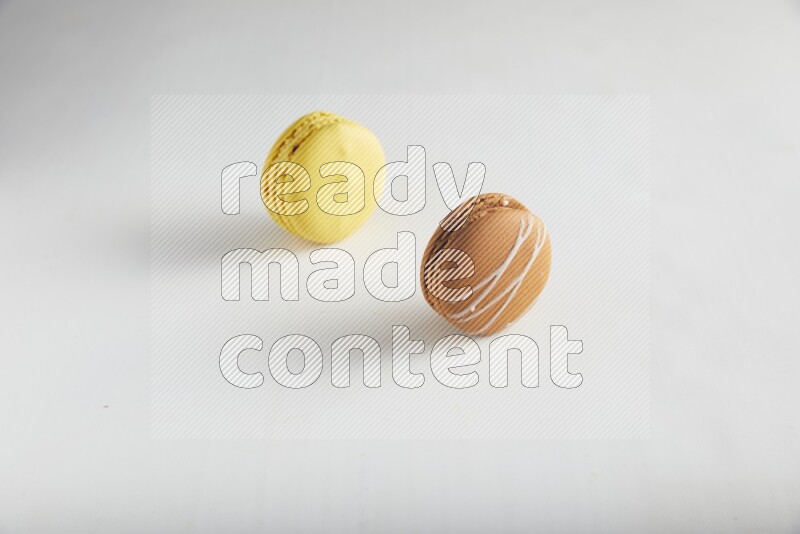 45º Shot of of two assorted Brown Irish Cream, and Yellow Lemon macarons on white background