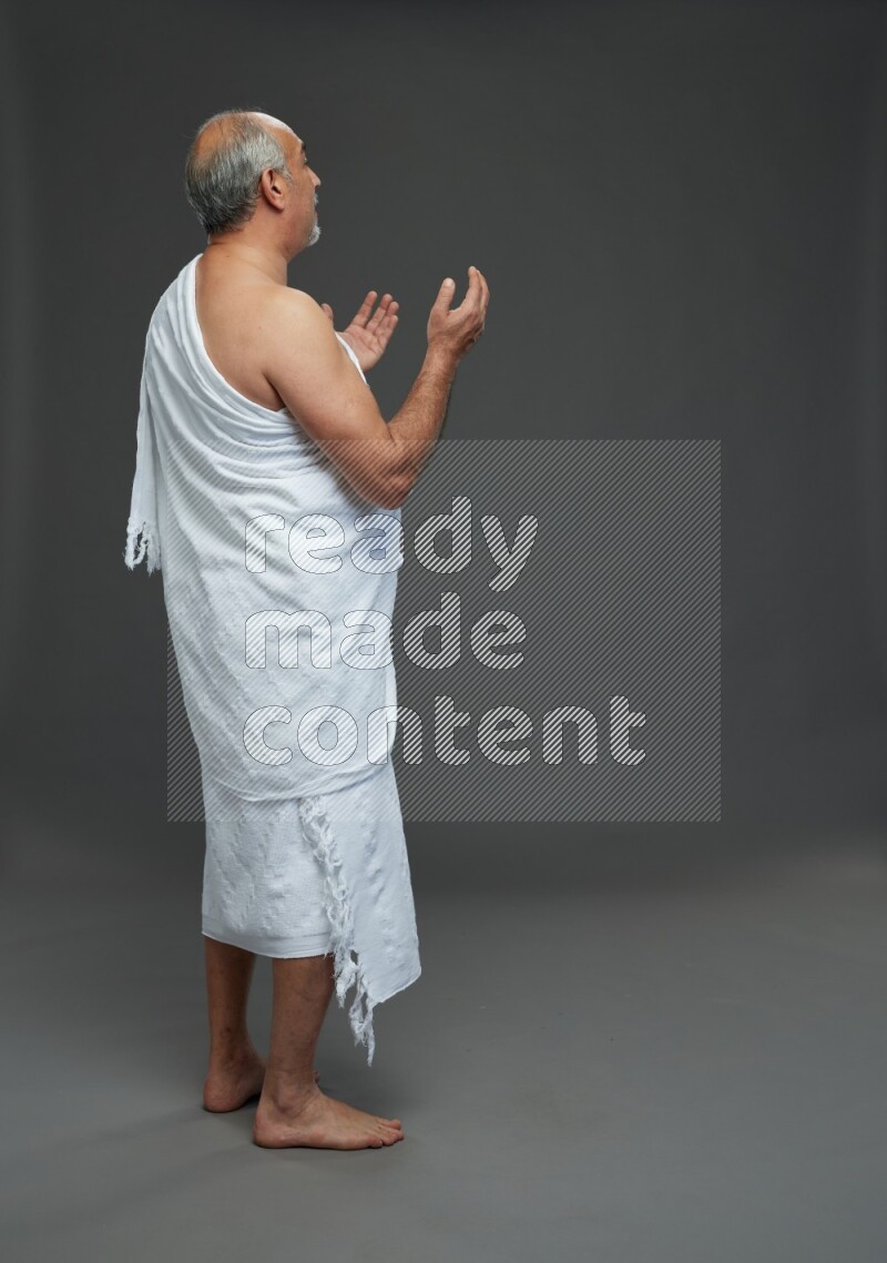 A man wearing Ehram Standing dua'a on gray background