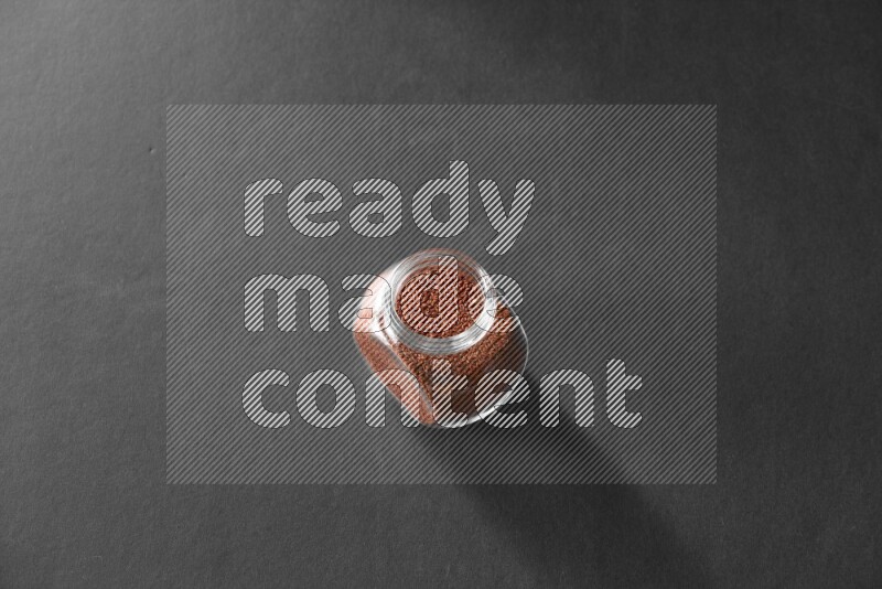 A glass spice jar full of garden cress on black flooring