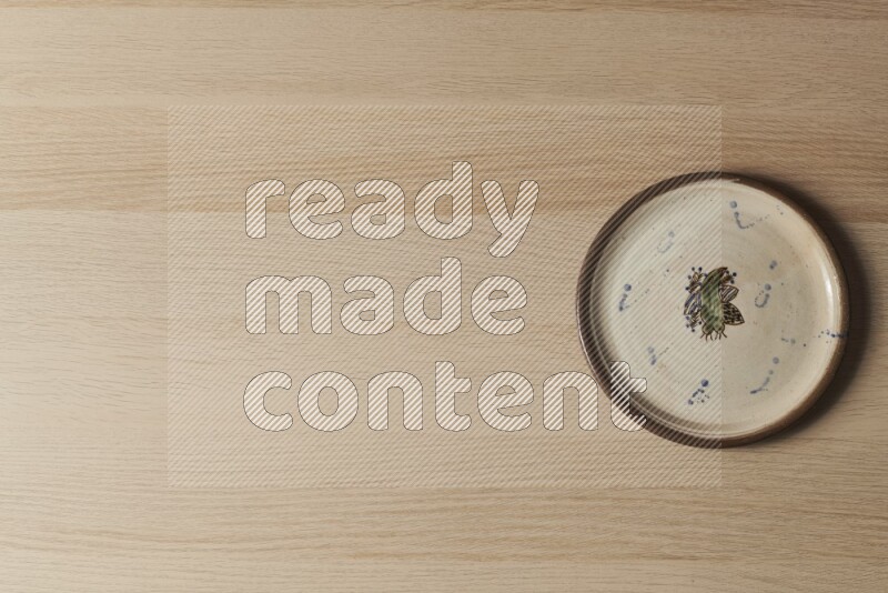 A decorative pottery plate on light wooden background