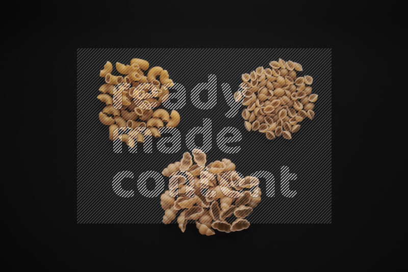 Different pasta types in bunches on black background