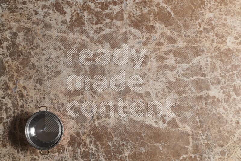 A small copper pot on beige marble background