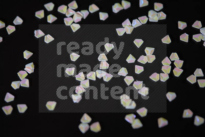 Colorful plastic shards for decoration scattered on a black background