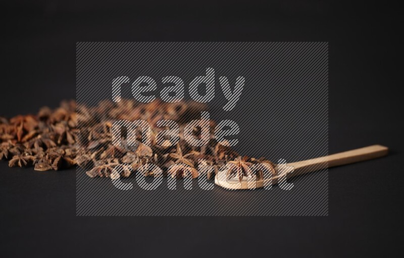 اليانسون النجمي في ملعقة خشبية ومتناثر على أرضية سوداء