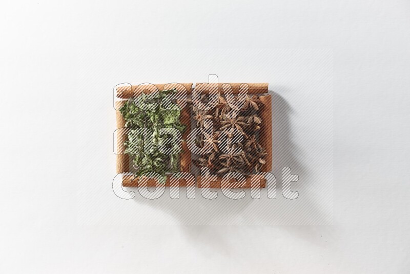 مربعان من أعواد القرفة ممتلئان باليانسون النجمي والنعناع المجفف علي خلفية بيضاء