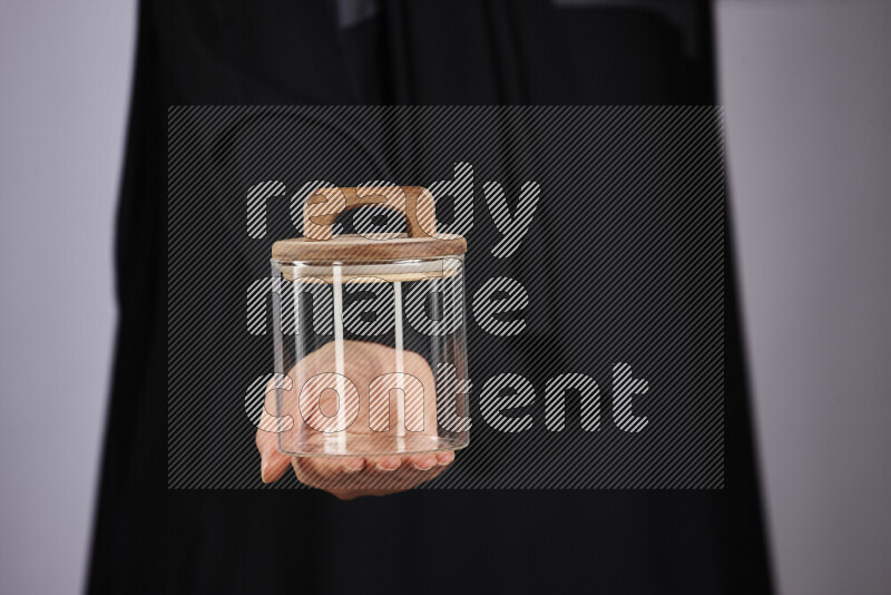 A woman in black abaya holding different glassware in different positions