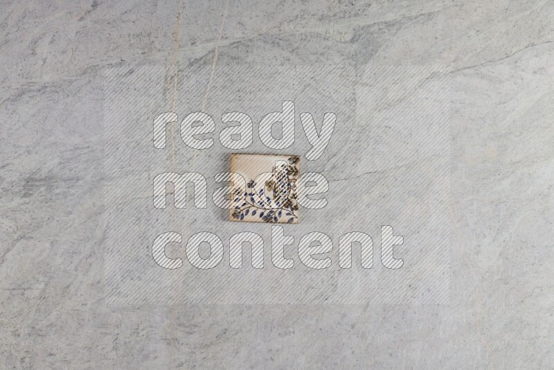 A decorative pottery coaster on grey marble background