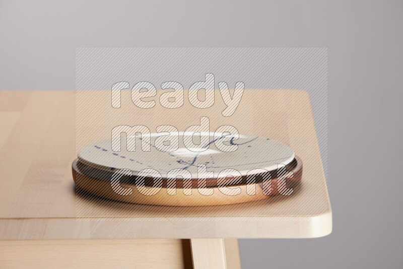 multi-colored pottery Plate placed on a light colored wooden tray on the edge of wooden table