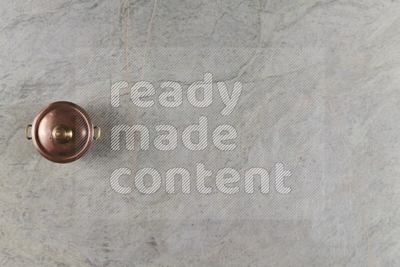 A small copper pot on grey marble background